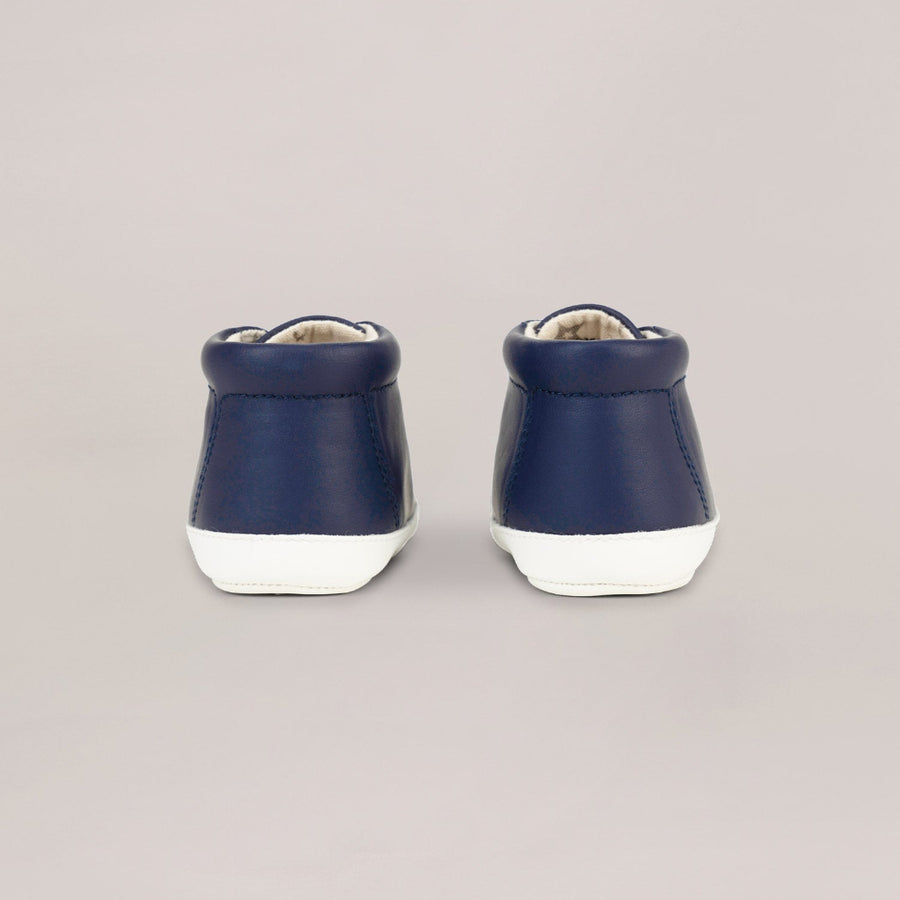 Pair of navy blue high-top shoes with white soles on a light gray background