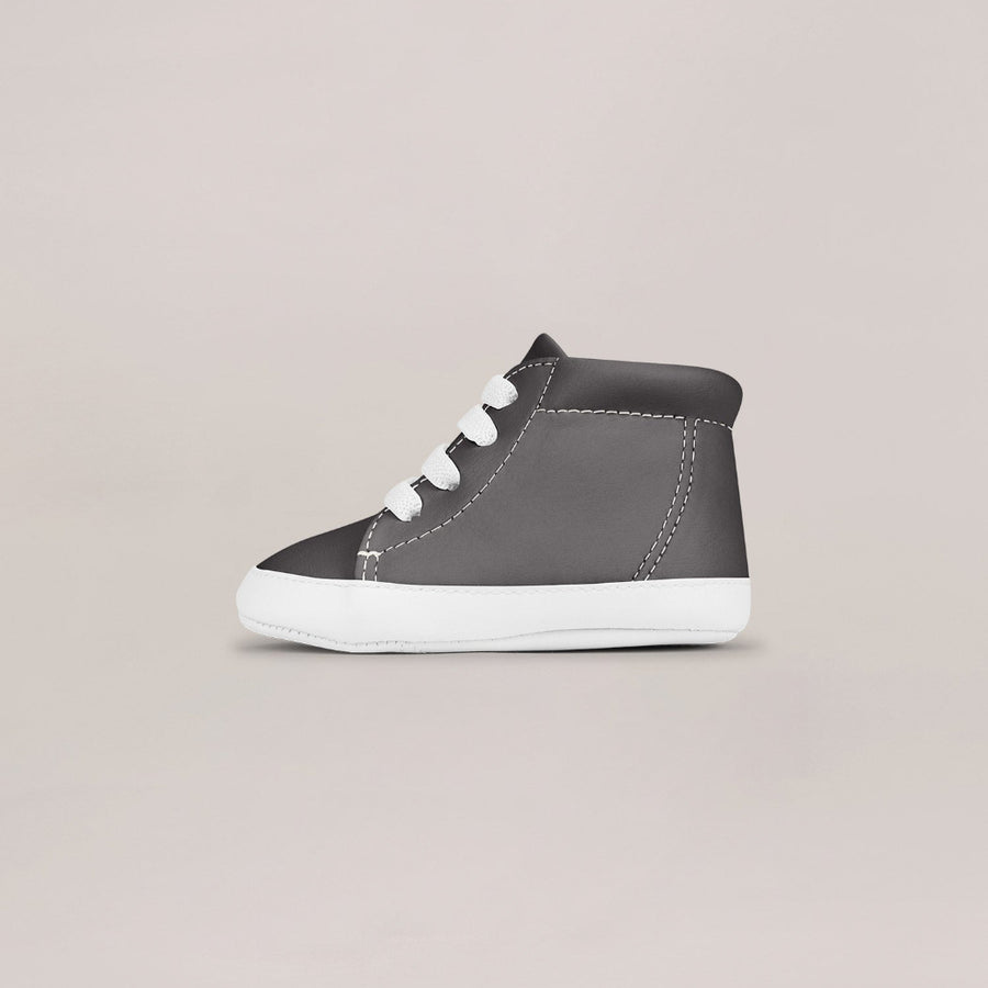 Gray high-top sneaker with white laces on a beige background