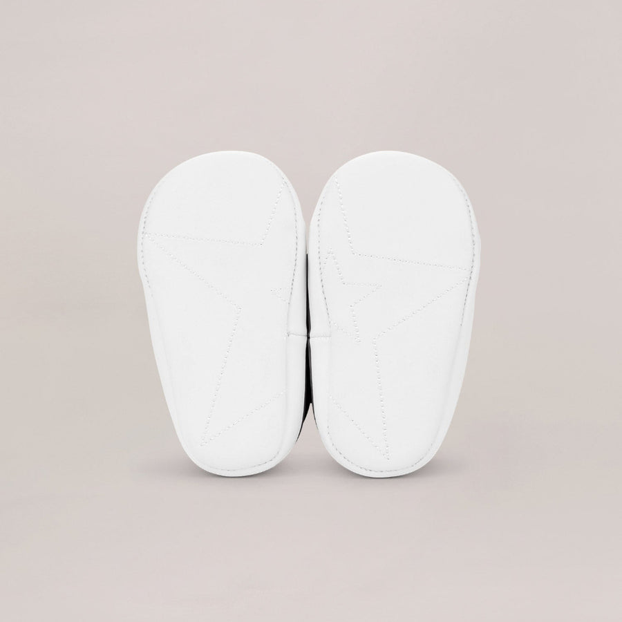 White soled shoes shown from below on a beige background