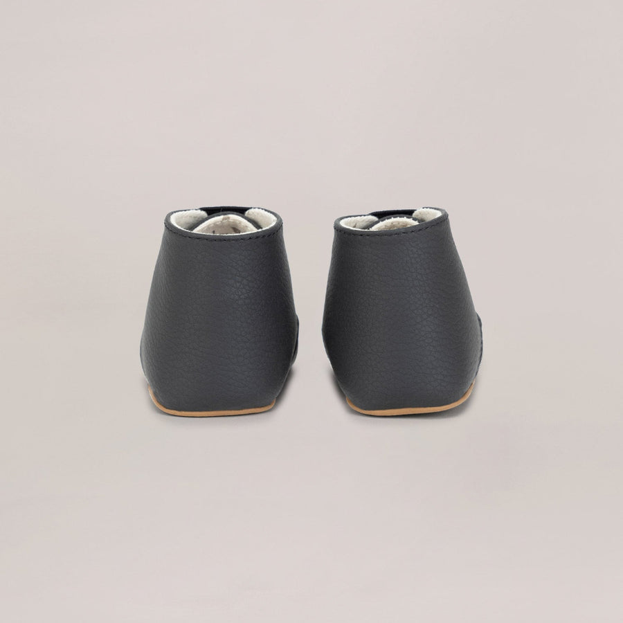 Pair of black leather shoes on a beige background