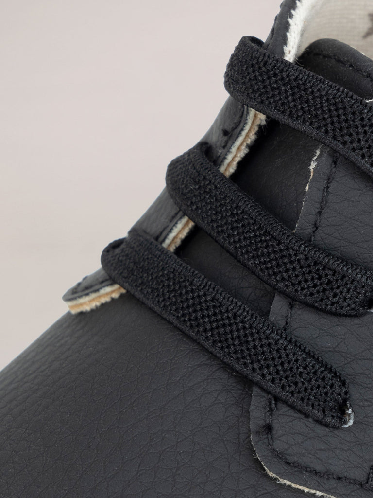 Close-up of black leather shoes with textured sole on a beige background