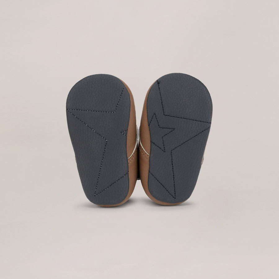 Pair of black soled shoes with a star design on a beige background