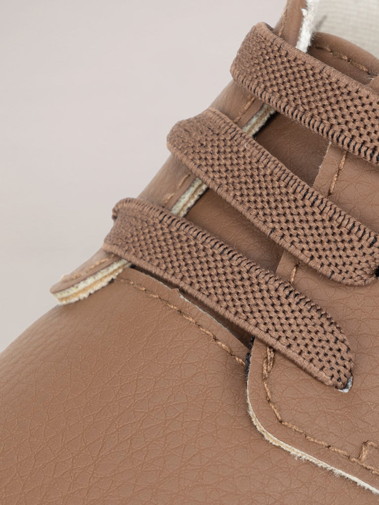 Close-up of brown leather shoe with velcro straps on a light pink background