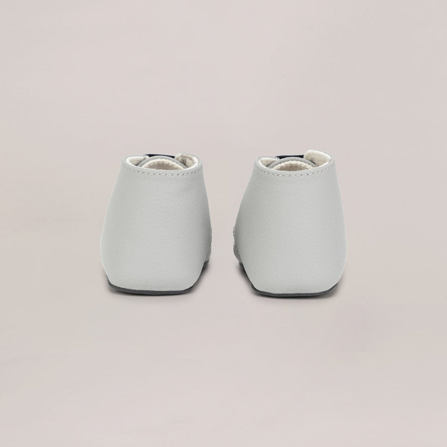 Pair of light gray baby shoes on a beige background