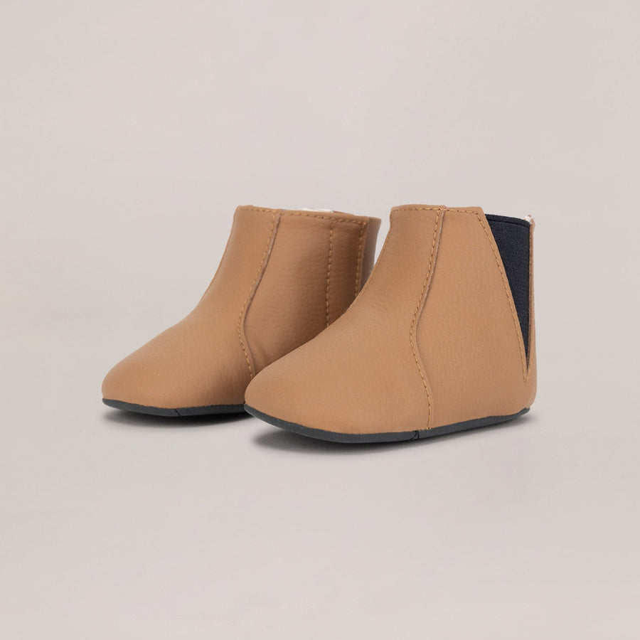 Pair of tan ankle boots on a beige background