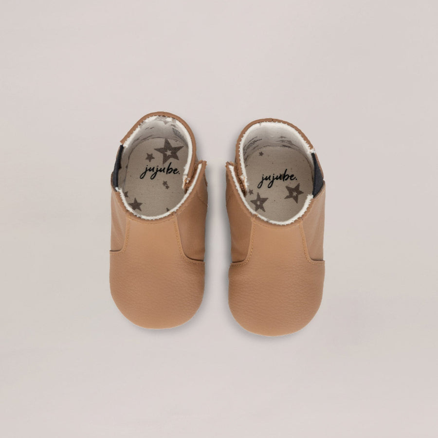 Pair of tan baby shoes with 'jujube' branding on a light gray background