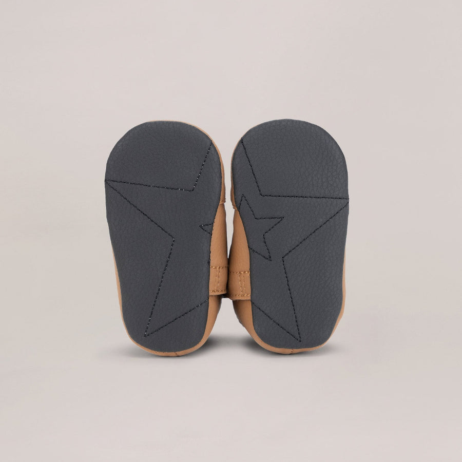 Pair of black soled shoes with brown uppers on a beige background