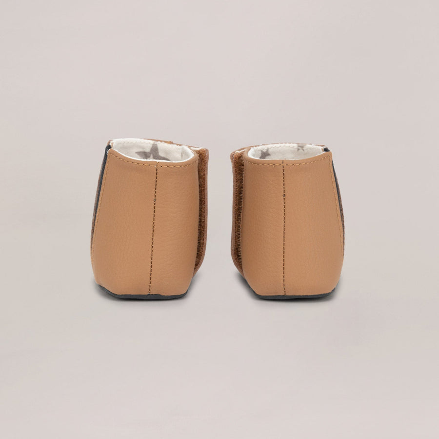 Pair of tan baby shoes on a light gray background