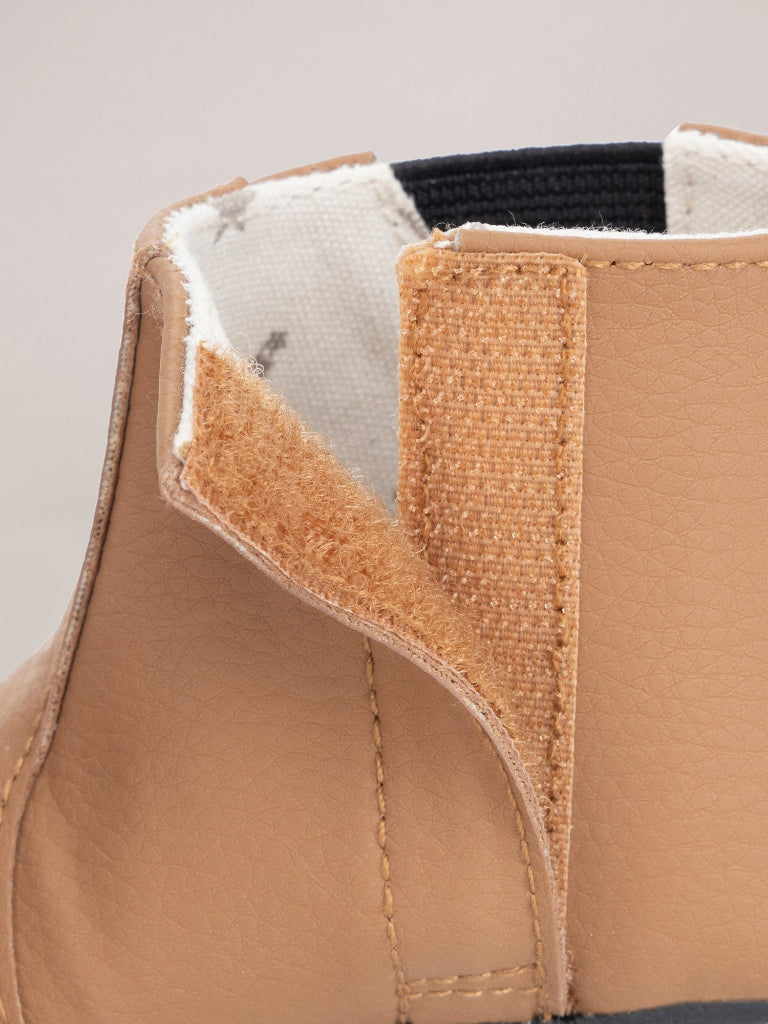 Close-up of a brown shoe with white lining and black trim on a light gray background