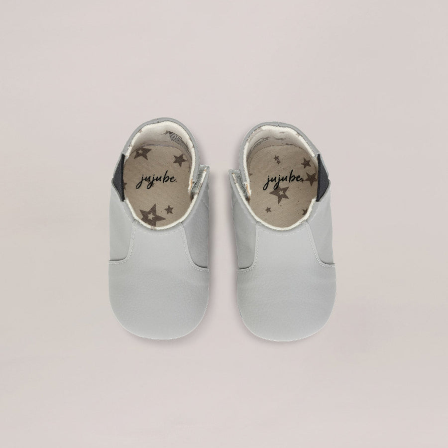 Pair of light gray baby shoes with 'jujube' branding on a white  background