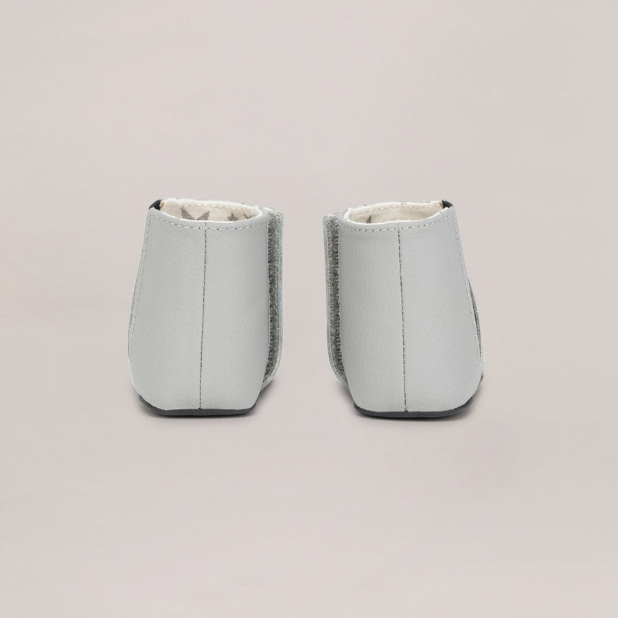 Pair of light gray baby shoes on a beige background