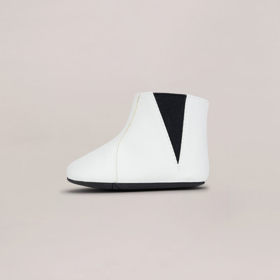 White ankle boot with black accent on a beige background
