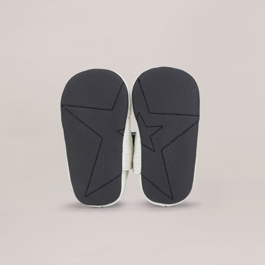 Black soled shoes with a geometric design on a beige background