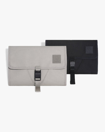 Picture of the front view of the taupe changing wallet with the black changing wallet behind it, on a white surface