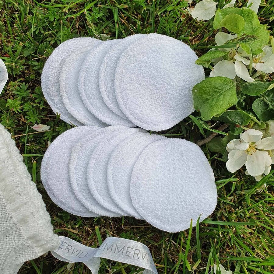 Set of white round cloths on grass with a visible brand name.