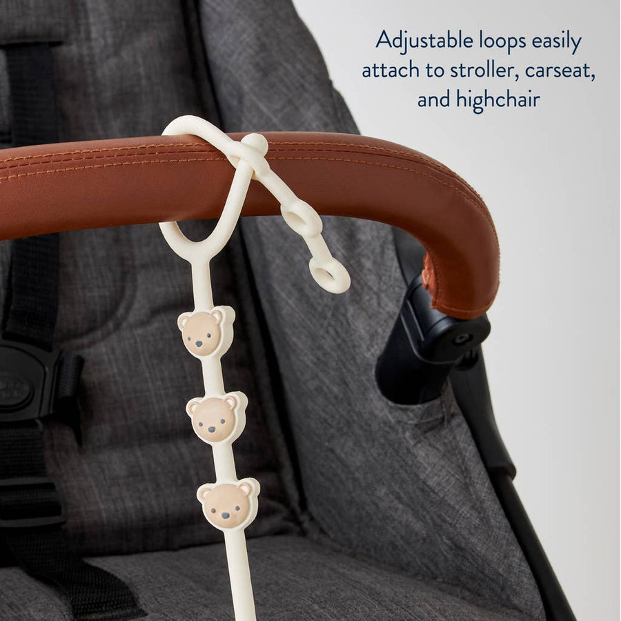 Stroller hook with bear designs attached to a stroller handle, with text indicating its use.