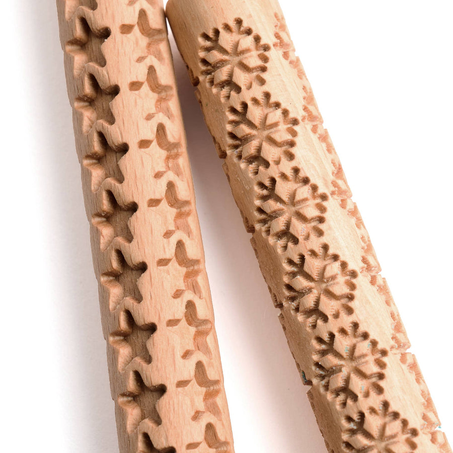 Two wooden embossing tools with intricate patterns on a white background