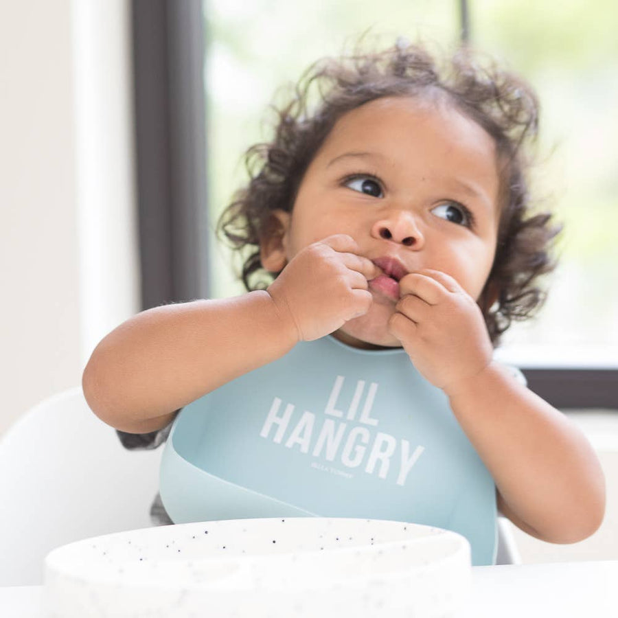 Baby wearing a 'LIL HANGRY' shirt sitting in a high chair.