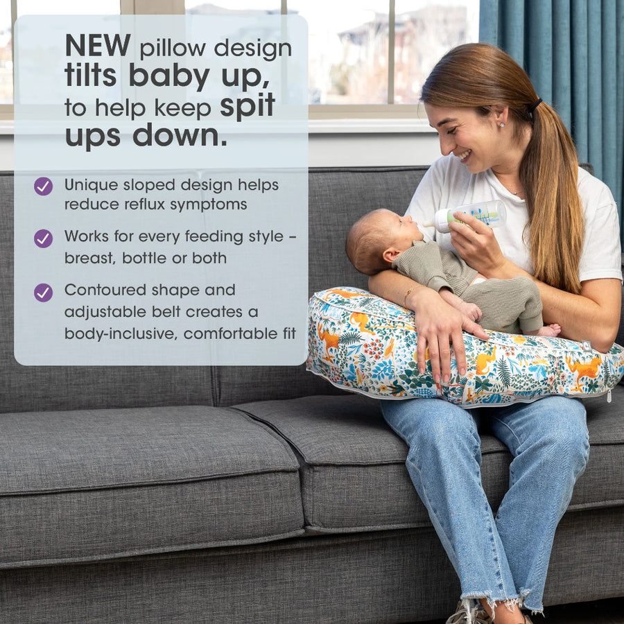 Woman holding a baby with a feeding pillow on a couch, text about pillow benefits.