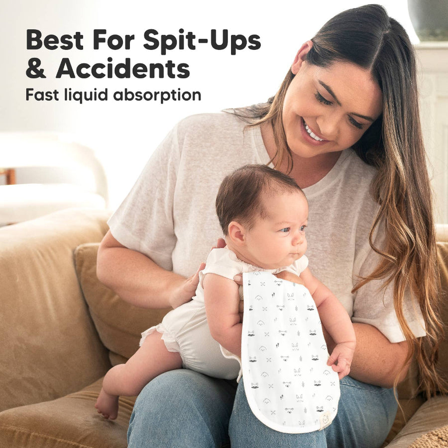 Woman holding a baby wearing a bib with text about spit-ups and accidents.