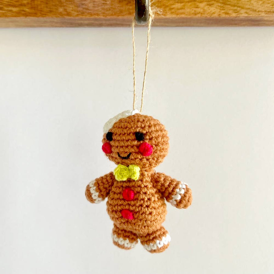 Crocheted gingerbread man ornament hanging on a white background