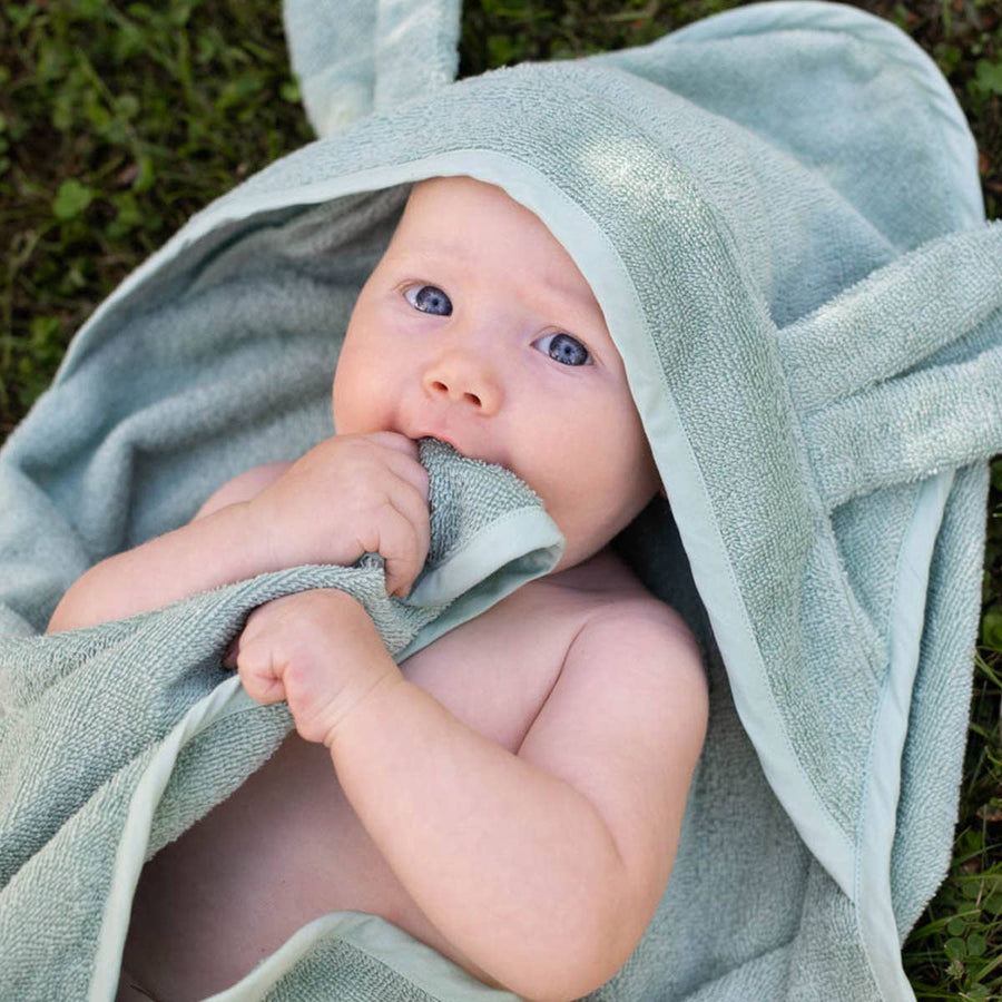 Baby wrapped in a light blue towel outdoors
