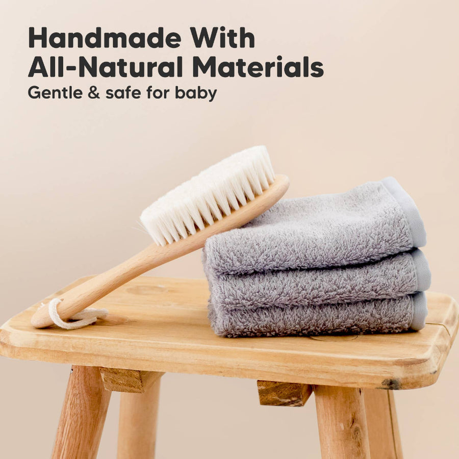 Baby bath brush and towels on a wooden stool with 'Handmade With All-Natural Materials' text.