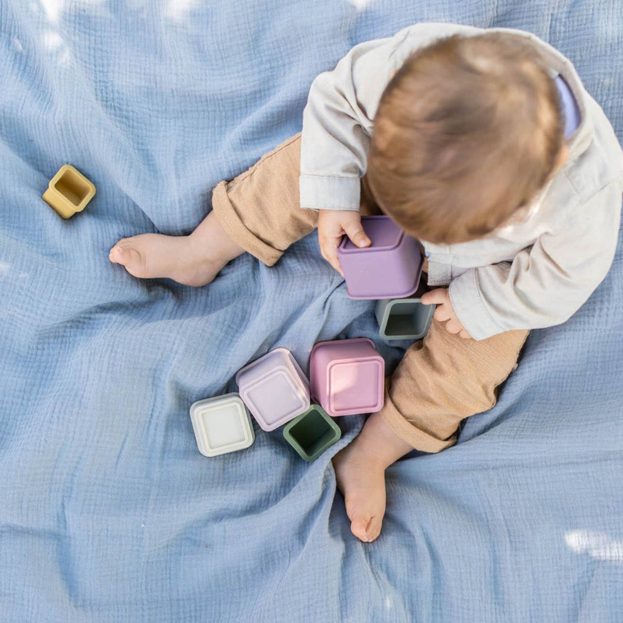 Child playing with colorful cups on a blue blanket