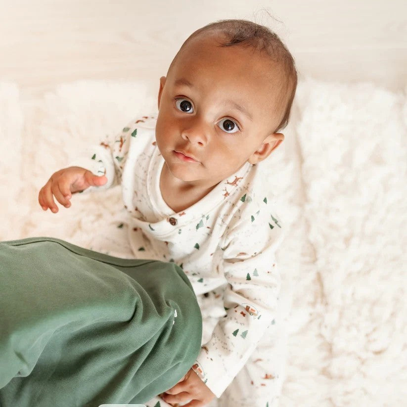 baby wearing the into the woods bodysuit with a sage colored blanket