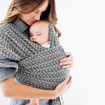 Picture of a woman wearing a Moby Evolution baby wrap with a black and white patterned print with infant