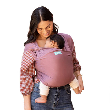 Picture of a woman wearing dusty pink colored baby wrap with infant