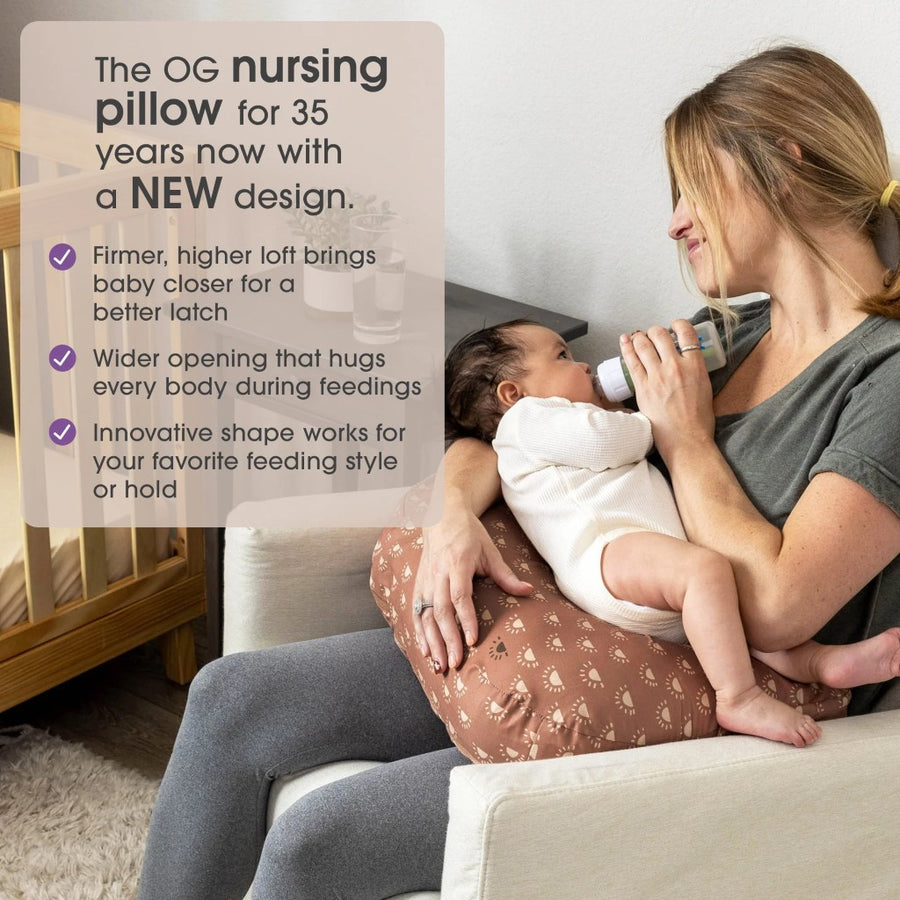 Woman holding a baby on a couch with text about a nursing pillow