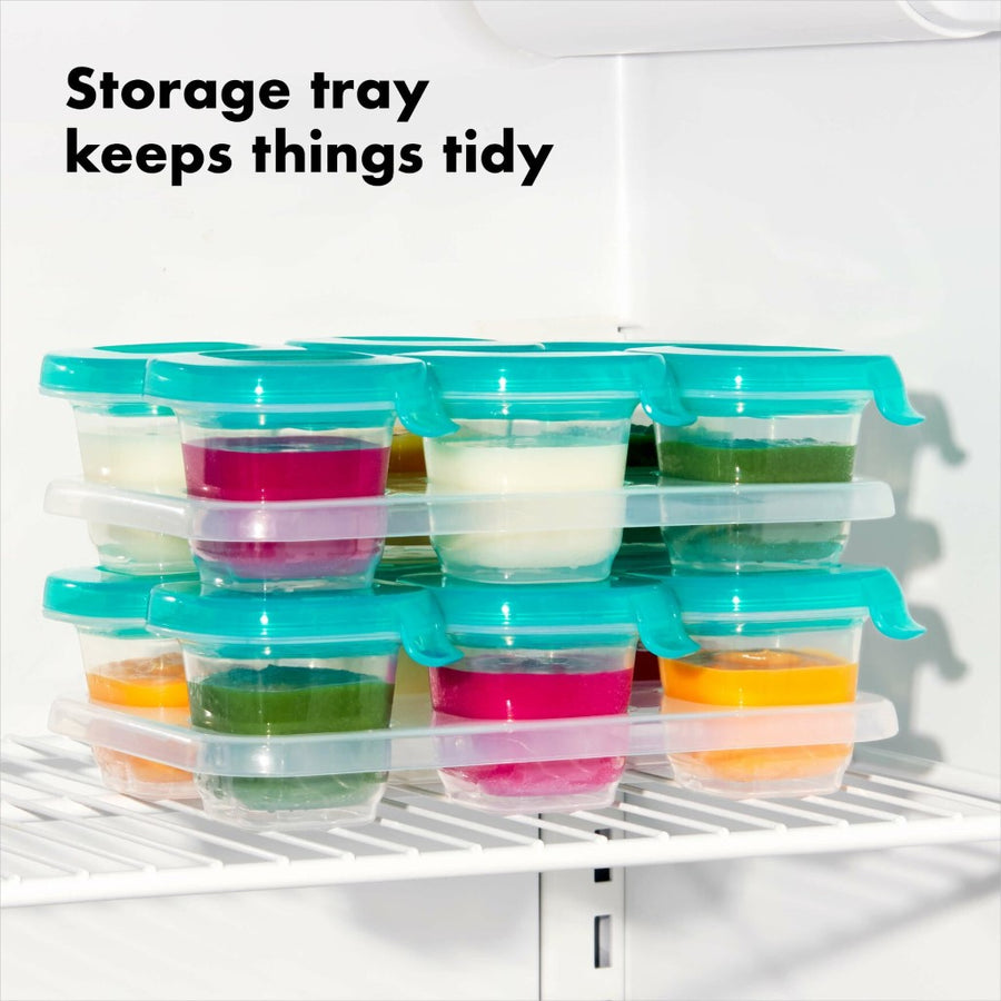Two sets of silicone baby blocks in their trays stacked in a freezer with text that reads, 