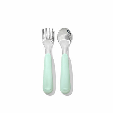 Baby fork and spoon with light green handles on a white background