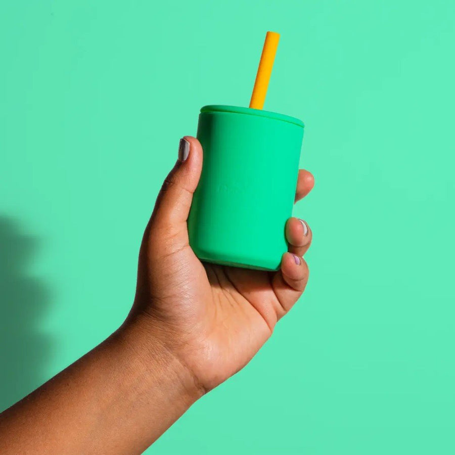 Hand holding the Avanchy Silicone Transition Cup in green