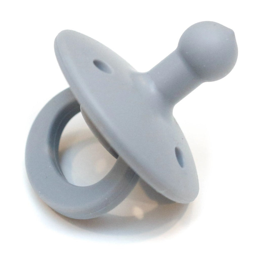 Picture of an OLI2 pacifier in a medium gray. It has a loop handle, a round flange with several holes, and a bulb-shaped nipple